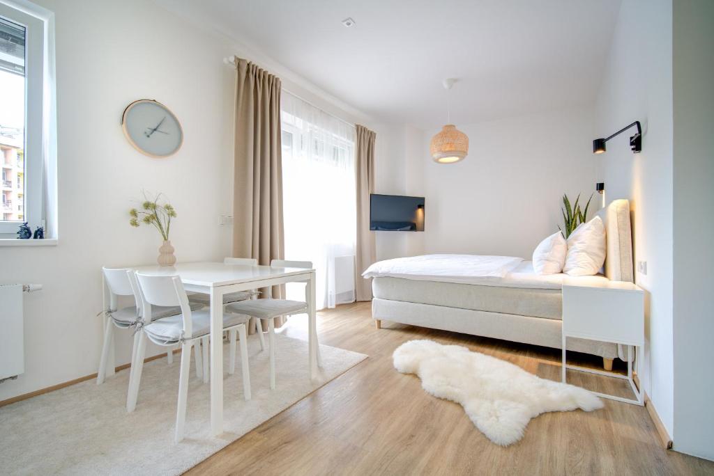 a white bedroom with a bed and a table at Urban Apartments in Brno
