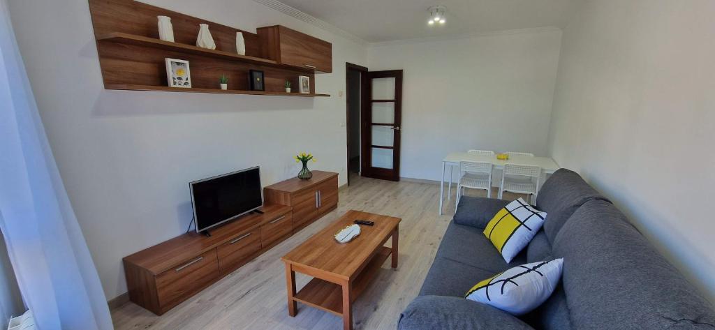 uma sala de estar com um sofá azul e uma televisão em Piso al lado de la playa em Boiro