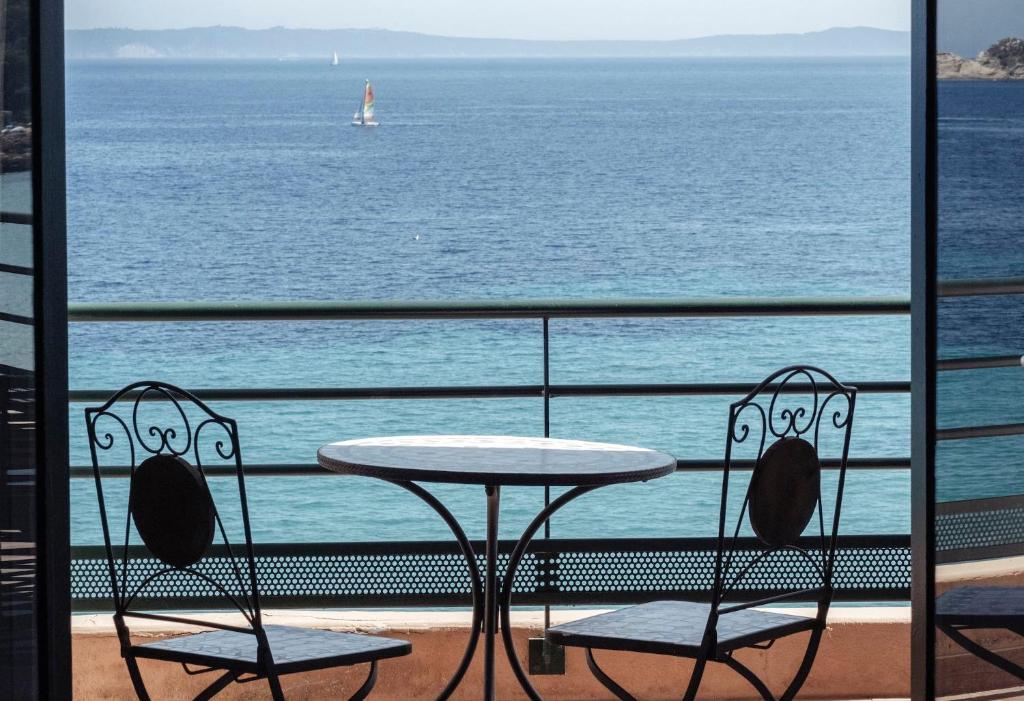 a table and chairs on a balcony overlooking the ocean at Surplage Hotel Cavalière in Le Lavandou