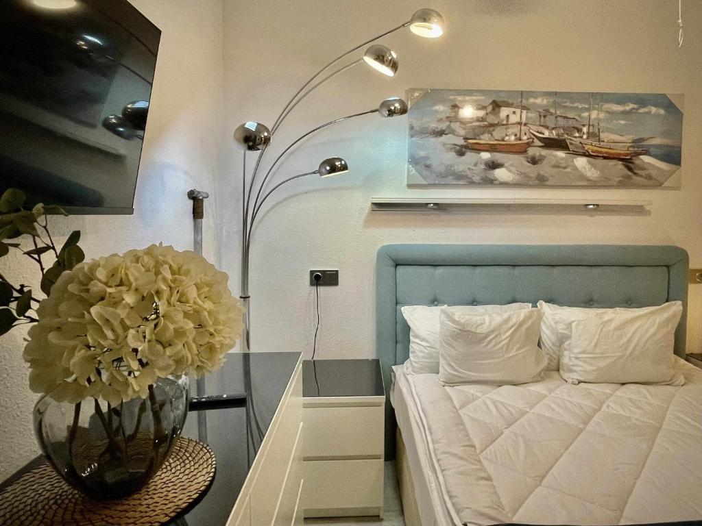 een slaapkamer met een bed en een vaas met bloemen bij El mundo soleado in Santa Pola