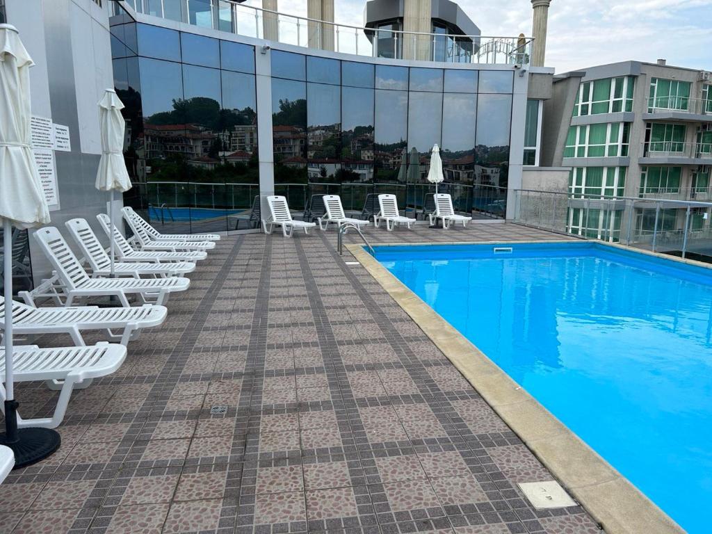 uma piscina no telhado de um edifício com espreguiçadeiras brancas em Byala Silver Beach Apart em Byala