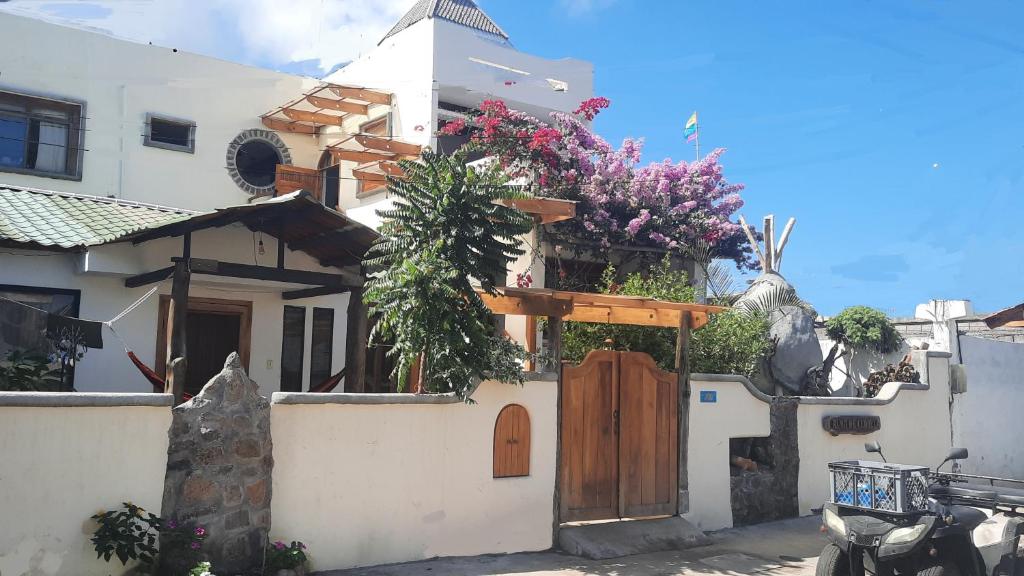 uma casa branca com uma porta de madeira e flores em Alma de cedrela em Puerto Ayora