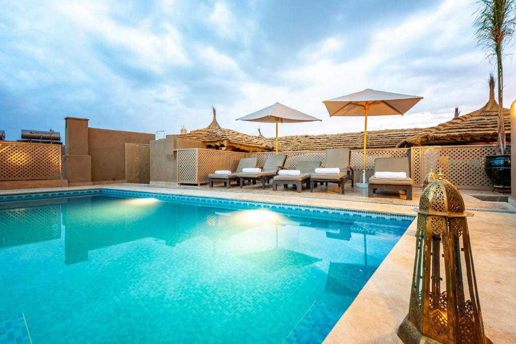 einen Pool mit Stühlen und Sonnenschirmen in einem Resort in der Unterkunft Palais Tara & Spa in Marrakesch