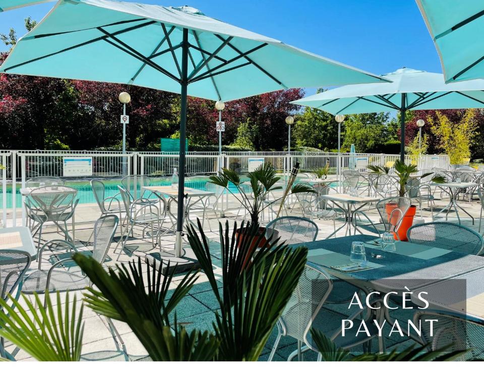 - un groupe de tables et de chaises avec des parasols et une piscine dans l'établissement Ibis Marne la Vallée Noisy, à Noisy-le-Grand