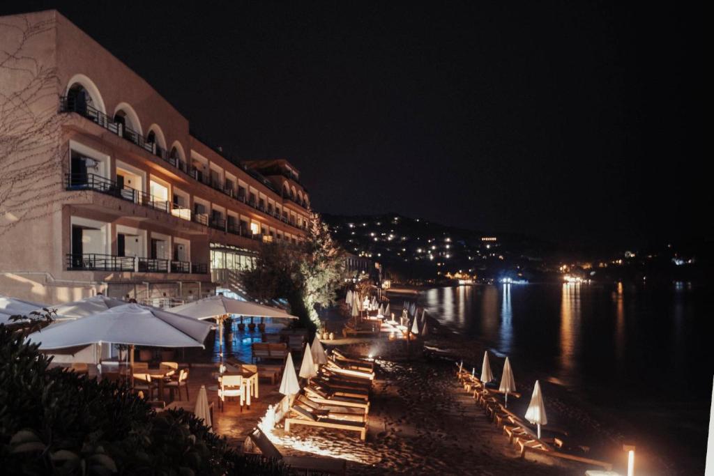 a building with tables and umbrellas next to a river at night at Surplage Hotel Cavalière in Le Lavandou