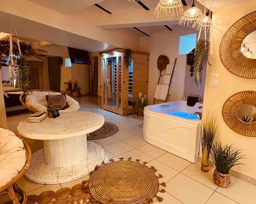 un soggiorno con tavolo e vasca da bagno di Magnifique appartement bohème / sauna / balneo a Valros