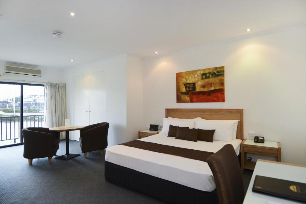 a hotel room with a bed and a table with chairs at BEST WESTERN Geelong Motor Inn & Serviced Apartments in Geelong