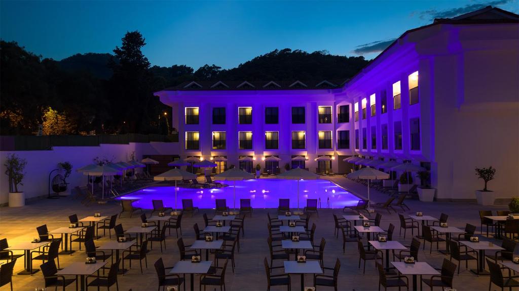 a group of tables and chairs in front of a building with purple lights at Saint Star Kemer - Adult Only in Kemer