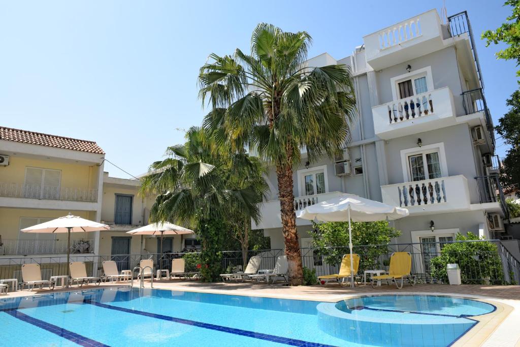 a hotel with a swimming pool in front of a building at Skalidis Apartments in Tolo