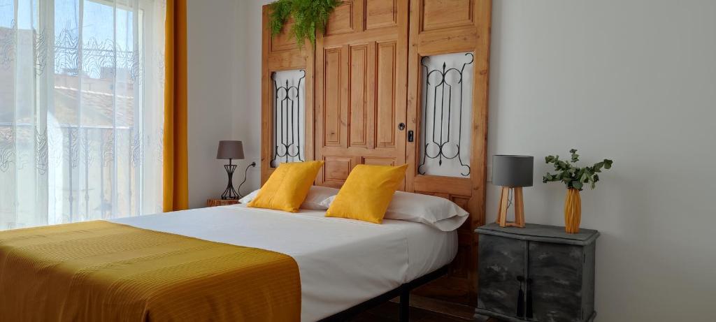 ein Schlafzimmer mit einem Bett mit gelben Kissen in der Unterkunft El Cantón in Bogarra