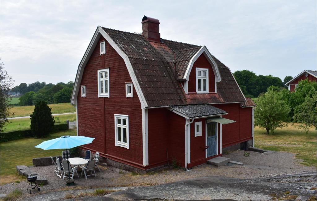 a red barn with a table and an umbrella at Lovely Home In Brkne-hoby With Wifi in Bräkne-Hoby