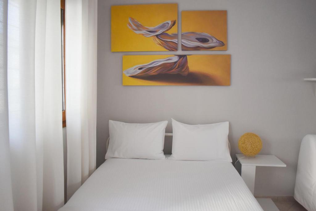 カヴァラにあるLina's Homeの白いベッドと絵画が備わるベッドルーム1室