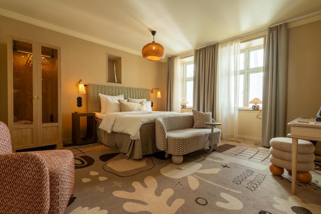 a bedroom with a bed and a chair and windows at Grand Joanne in Copenhagen