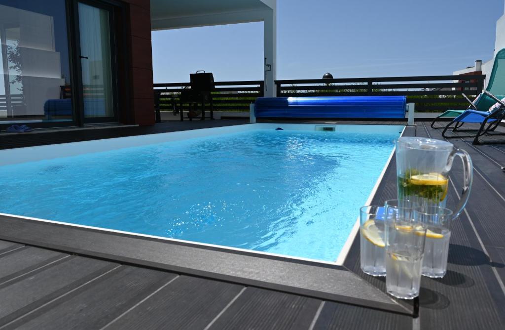 a swimming pool with glasses of wine and drinks on a deck at Luxury Oceanview Villa with Private Pool in Ericeira