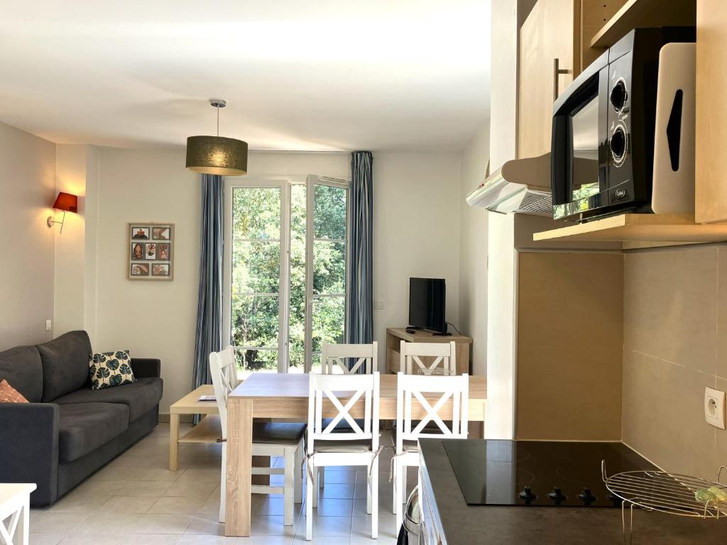 a kitchen and living room with a table and a couch at Les Maisons du Golf de la Cabre d'Or by Ateya Vacances in Cabriès
