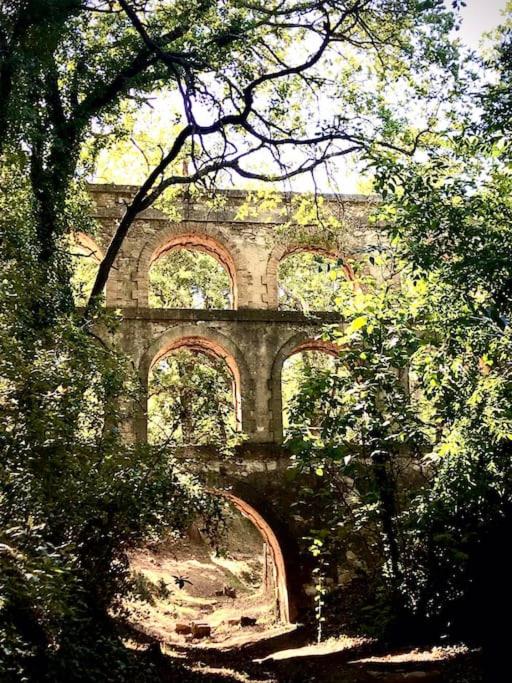 an old stone building with an archway in a forest at La Balouvière Villa entre Cévennes et Provence in Laudun