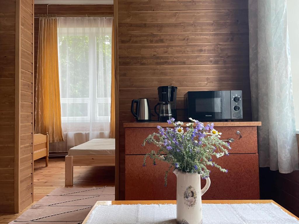 ein Wohnzimmer mit einer Blumenvase auf dem Tisch in der Unterkunft Võhma Külamaja in Võhma