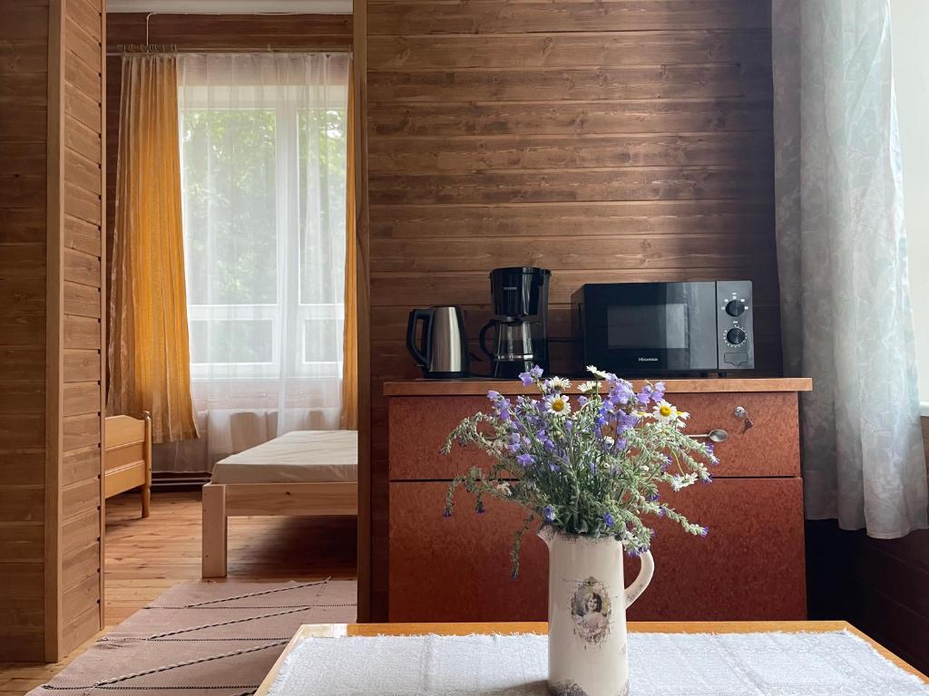 uma sala de estar com um vaso de flores sobre uma mesa em Võhma Külamaja em Võhma