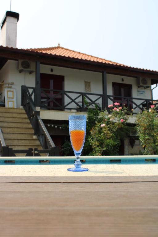 a glass of orange juice sitting on a table next to a pool at Casa da Aldeia da Avó in Valpaços