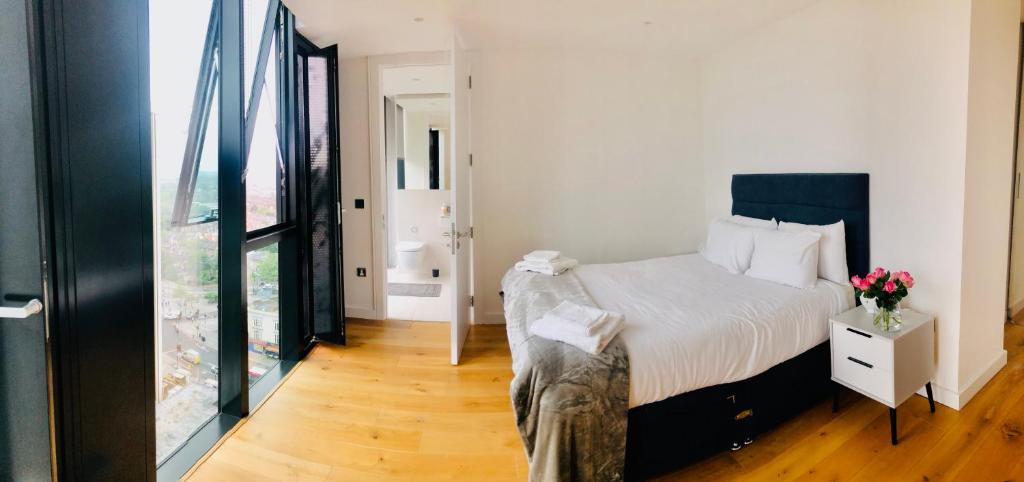 a bedroom with a bed and a glass door at Luxury 2 bedroom apartment 20 min from central London in London