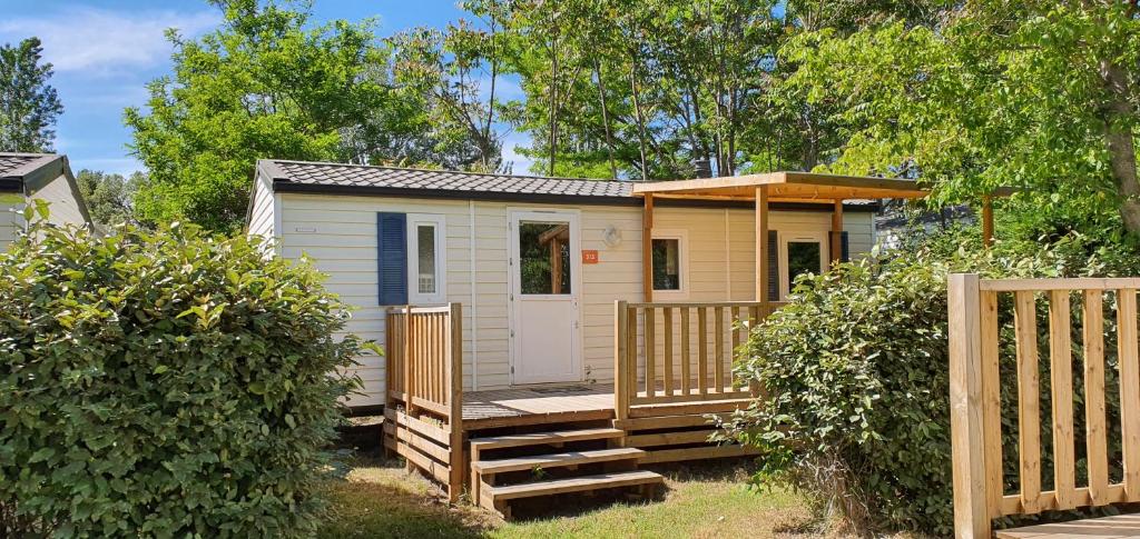 une petite maison avec un porche et une clôture dans l'établissement Mobil Home climatisé 6 personnes, à La Roque-dʼAnthéron