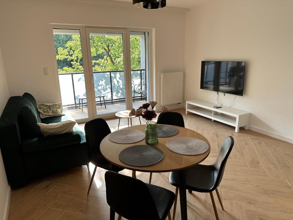 een woonkamer met een tafel en stoelen en een televisie bij Green Metropolis in Toruń