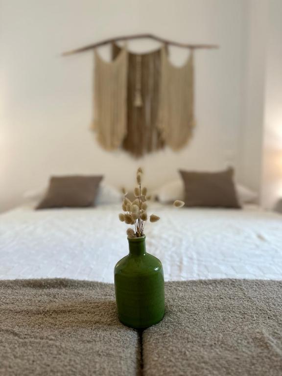a green vase with a plant on a bed at Valente Rooms Kythira in Kythira
