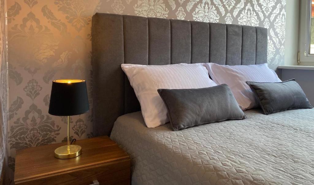 a bed with two pillows and a lamp on a table at Villa Orłowska Apartamenty in Gdynia