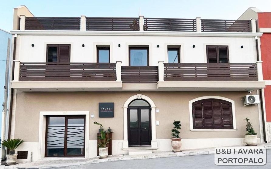 a large white building with wooden balconies on it at FAVARA Rooms in Portopalo