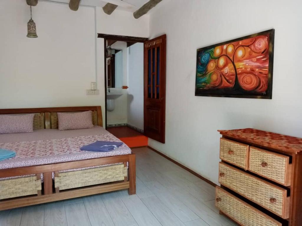 um quarto com uma cama e um quadro na parede em Kokrobite Gardens Restaurant and Guest House em Kokrobite