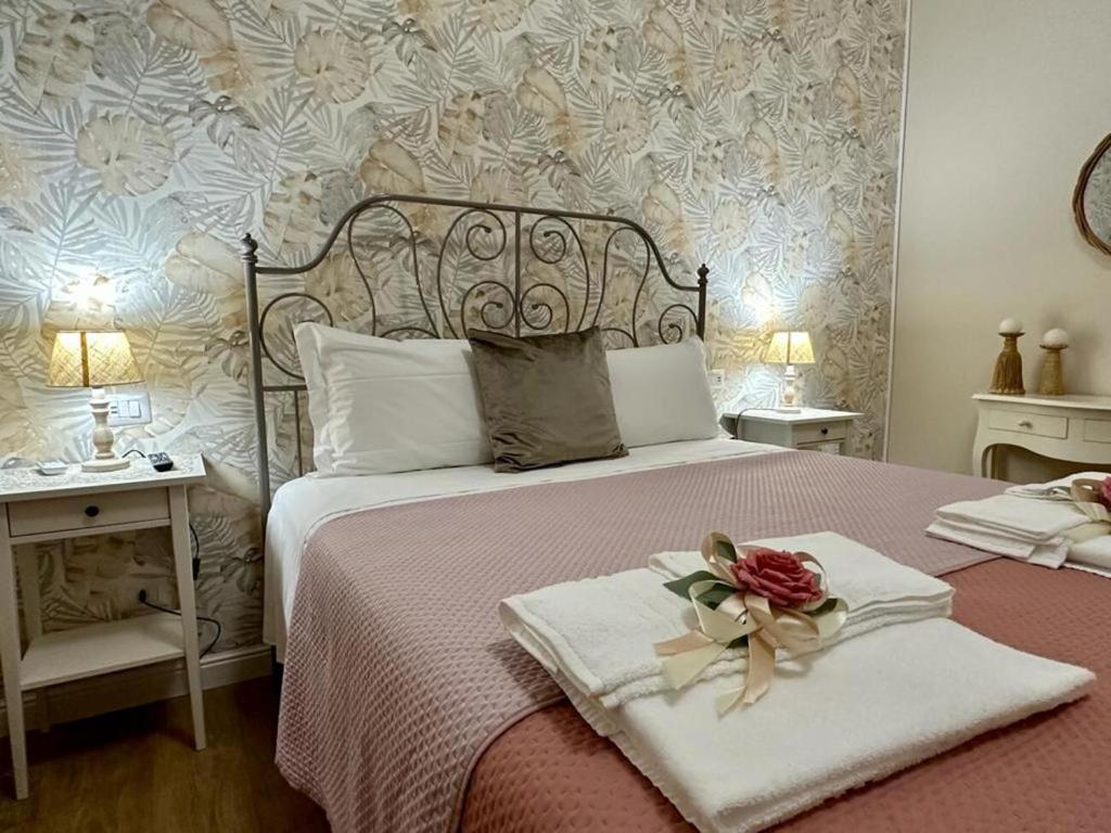a bedroom with a bed with a flower on it at Olympus Pompei Rooms in Pompei