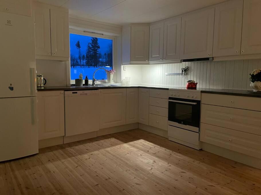 cocina con armarios blancos y ventana grande en Koselig gammelt hus på gård 