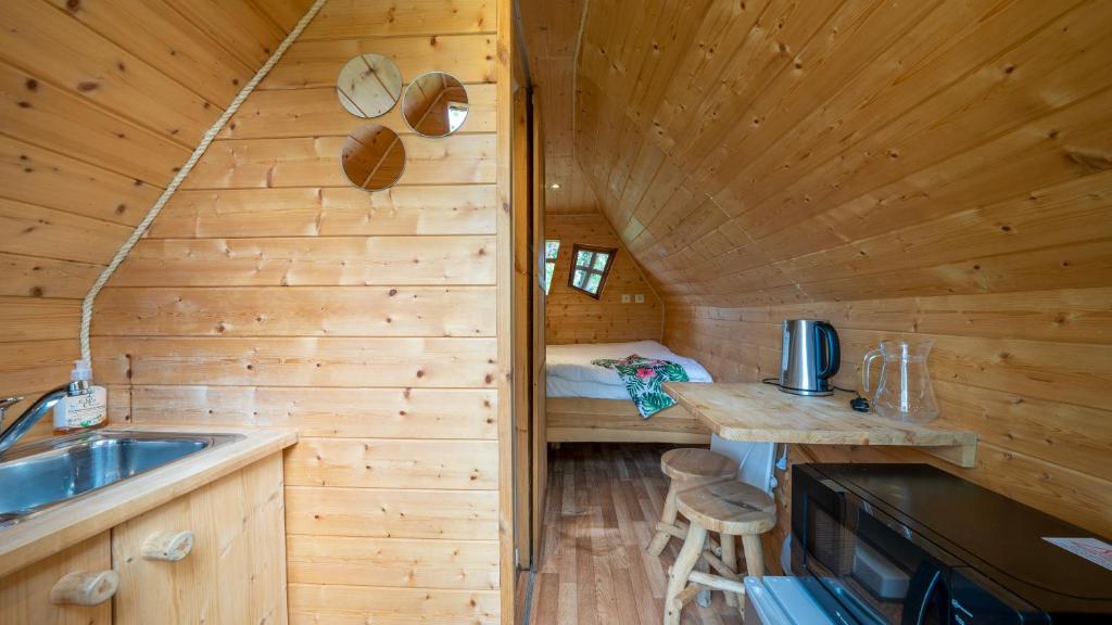 uma cozinha de chalé de madeira com um lavatório e uma cama em Village Toue du Domaine des Demoiselles em Chassenard