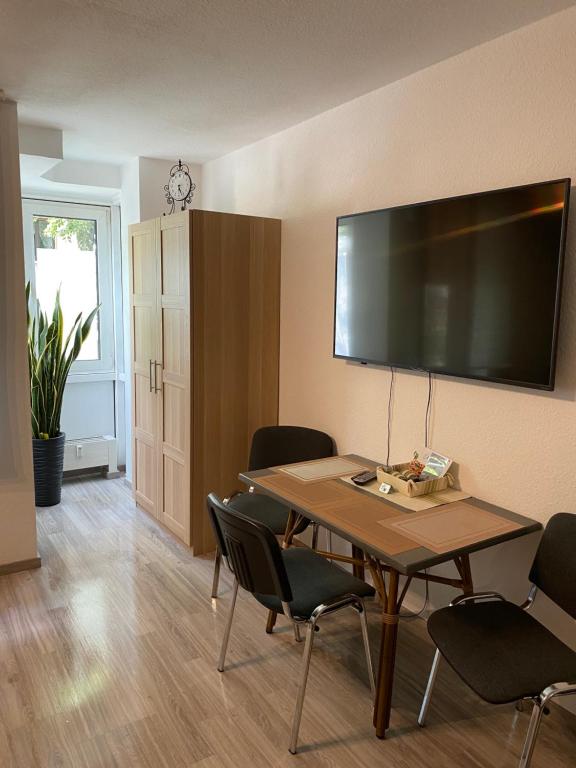 Habitación con mesa con sillas y TV grande en la pared. en Hüls Central Apartment, en Marl