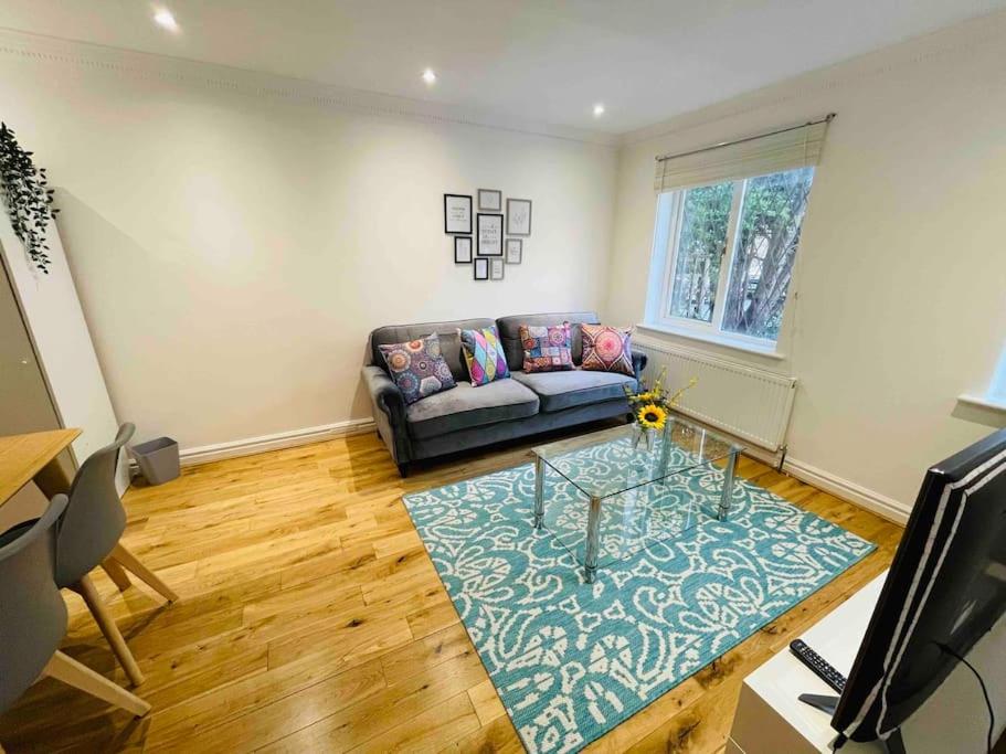 uma sala de estar com um sofá e uma mesa em Modern cosy house /free parking for two cars/ 3 minutes walk to the underground em Londres