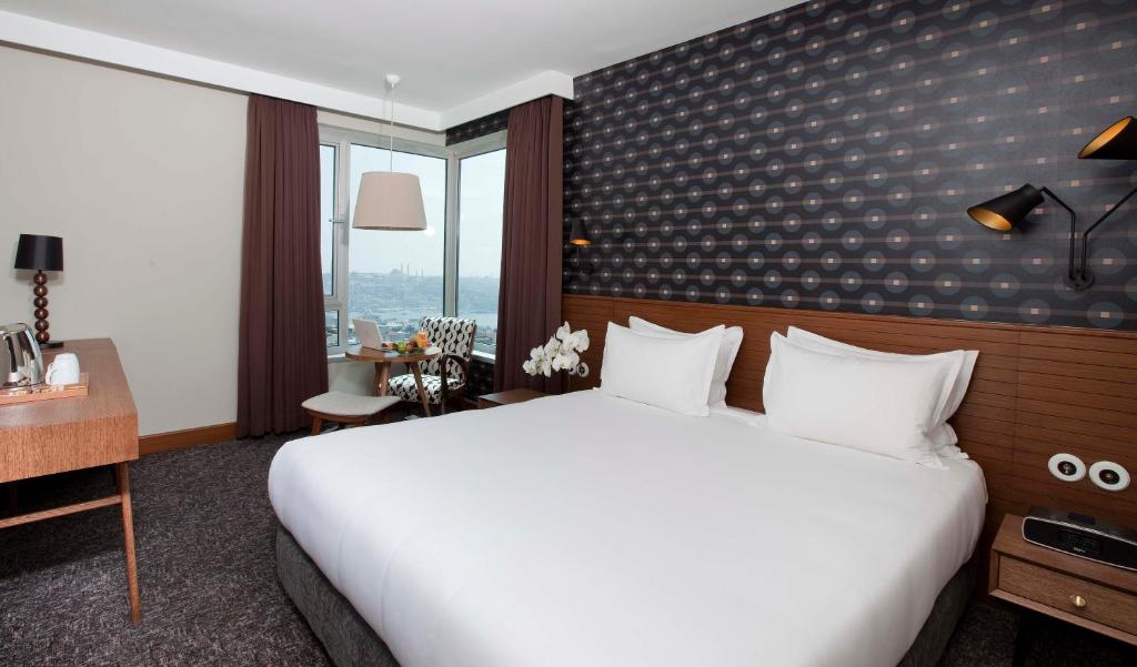a hotel room with a large white bed and a desk at The Marmara Pera in Istanbul