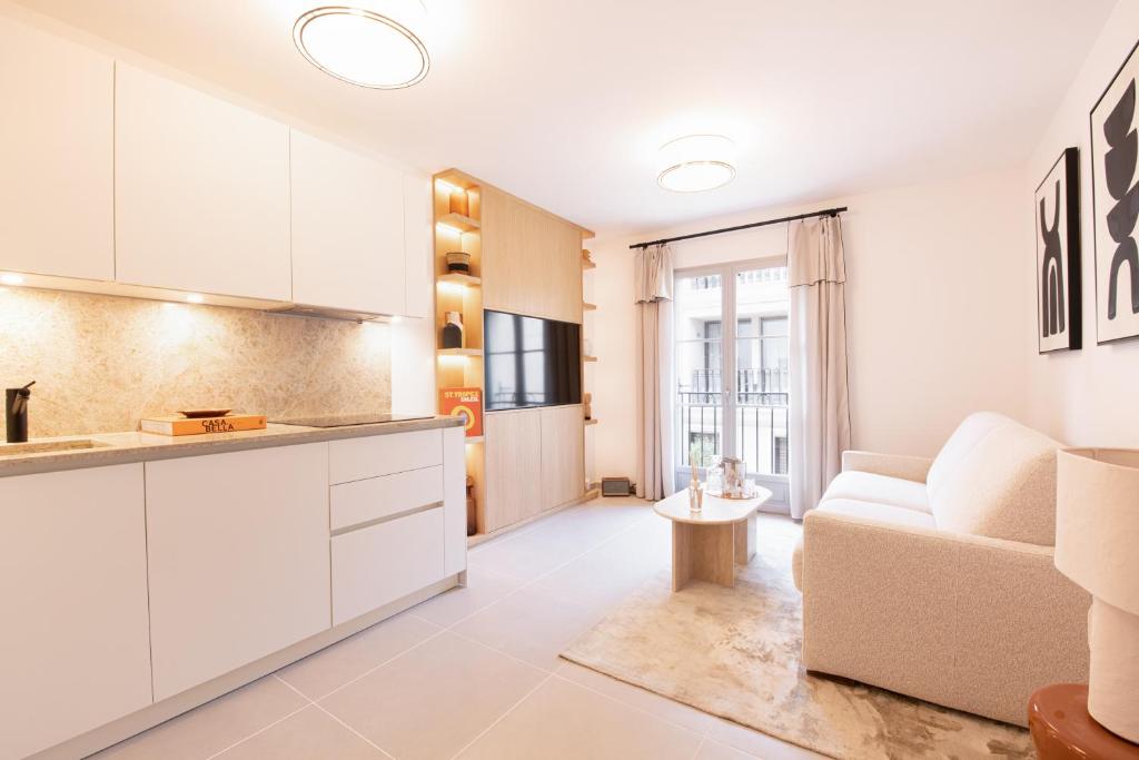 Il comprend une cuisine et un salon avec des placards blancs et un canapé. dans l'établissement OSCAR, appartement de standing, à Saint-Tropez