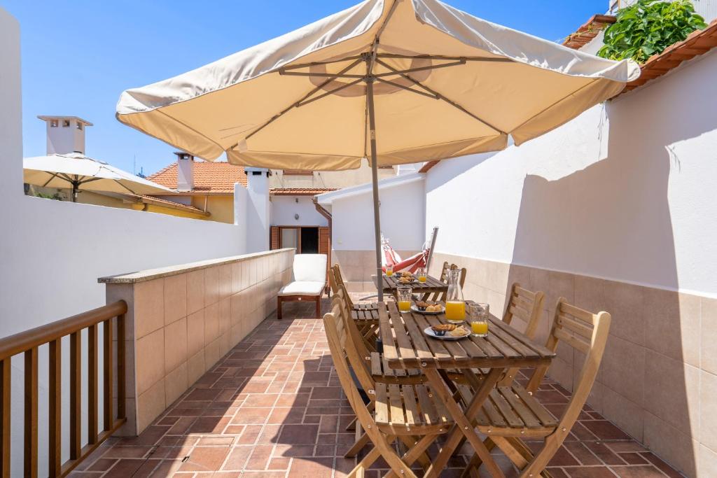 - une table en bois avec un parasol sur le balcon dans l'établissement Spacious Duplex House - Jacuzzi & Terrace, à Porto