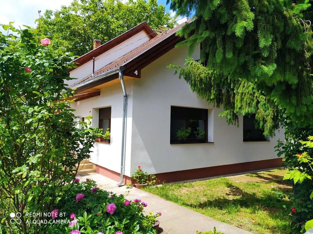 a white house with trees and flowers at Dóra Apartman in Balatonszárszó