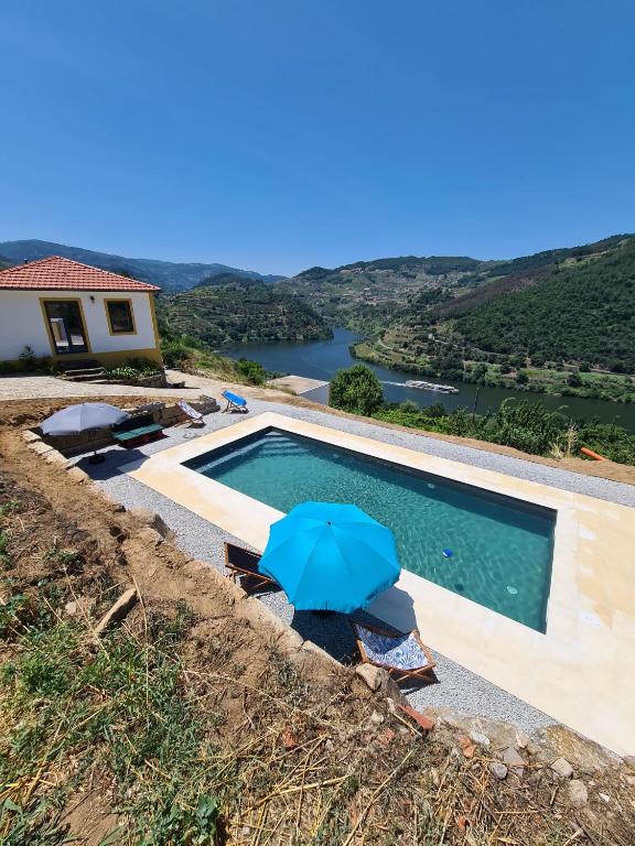 a swimming pool with a blue umbrella next to a house at Quinta do Fojo Valonguinho, Barrô in Barrô