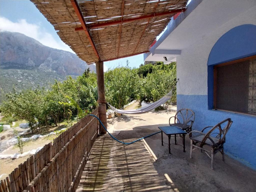 un porche de una casa con sillas y hamaca en Caiat Lounge Refuge en Oued Taghzoute