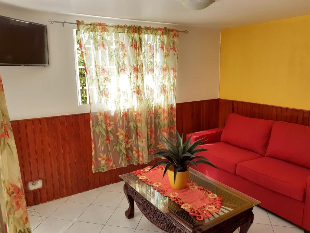 - un salon avec un canapé rouge et une table dans l'établissement La verdure, au Gosier