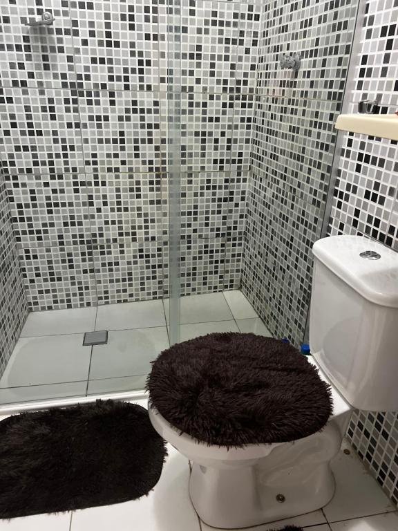 a bathroom with a shower with a toilet and two rugs at Localizada no centro de Juazeiro in Juazeiro