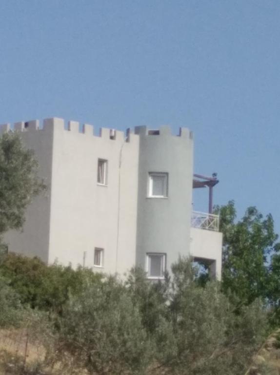 a white building on top of a hill with trees at el castle in Agioi Apostoli