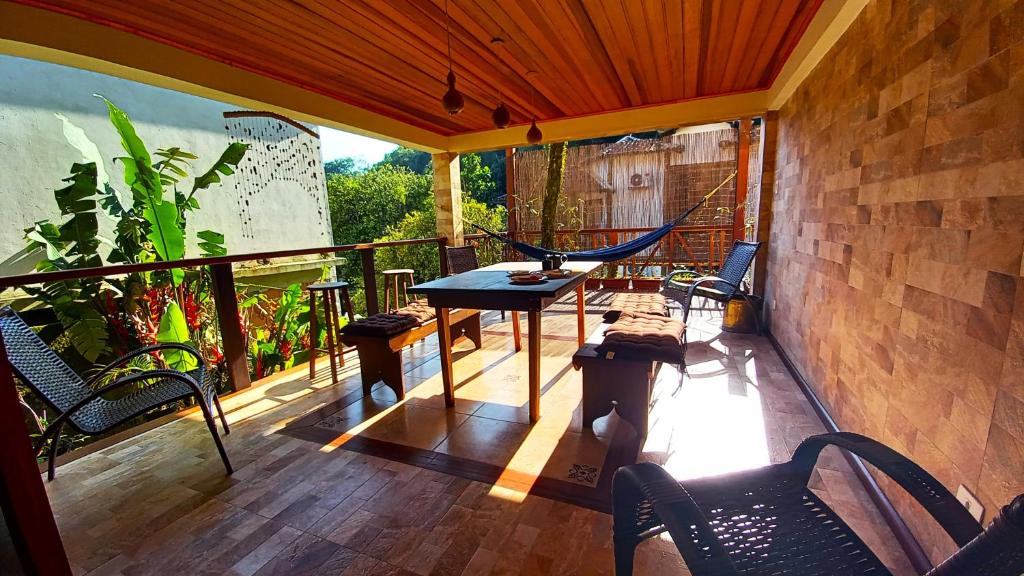 balcón con hamaca, mesa y sillas en Casa Iluminalia, en Abraão