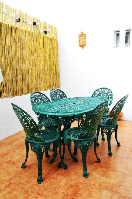 a table and chairs with a green table and chairs at Casa do Jardim in Montargil