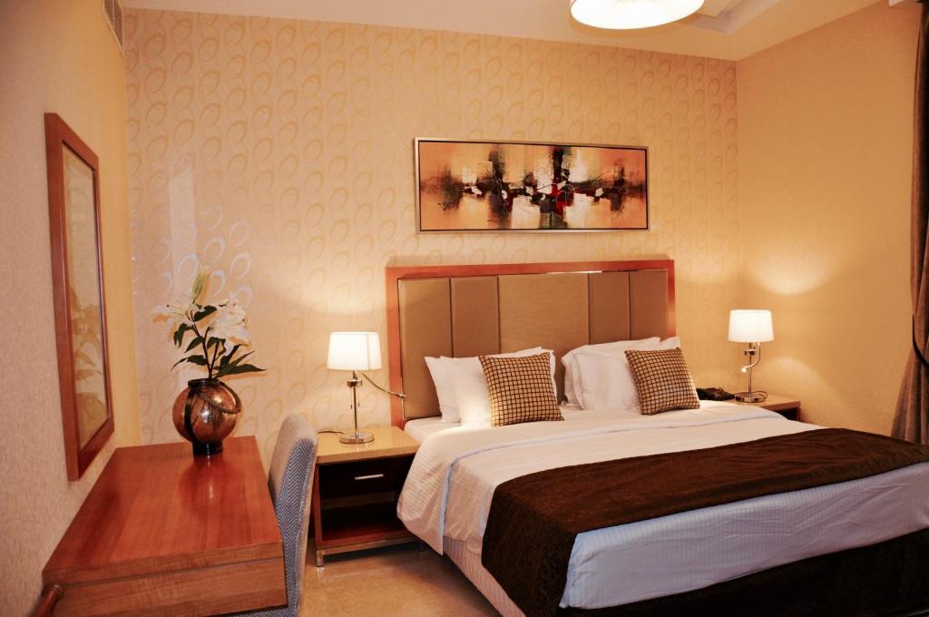 a bedroom with a bed and a table with two lamps at Asherij Hotel in Doha