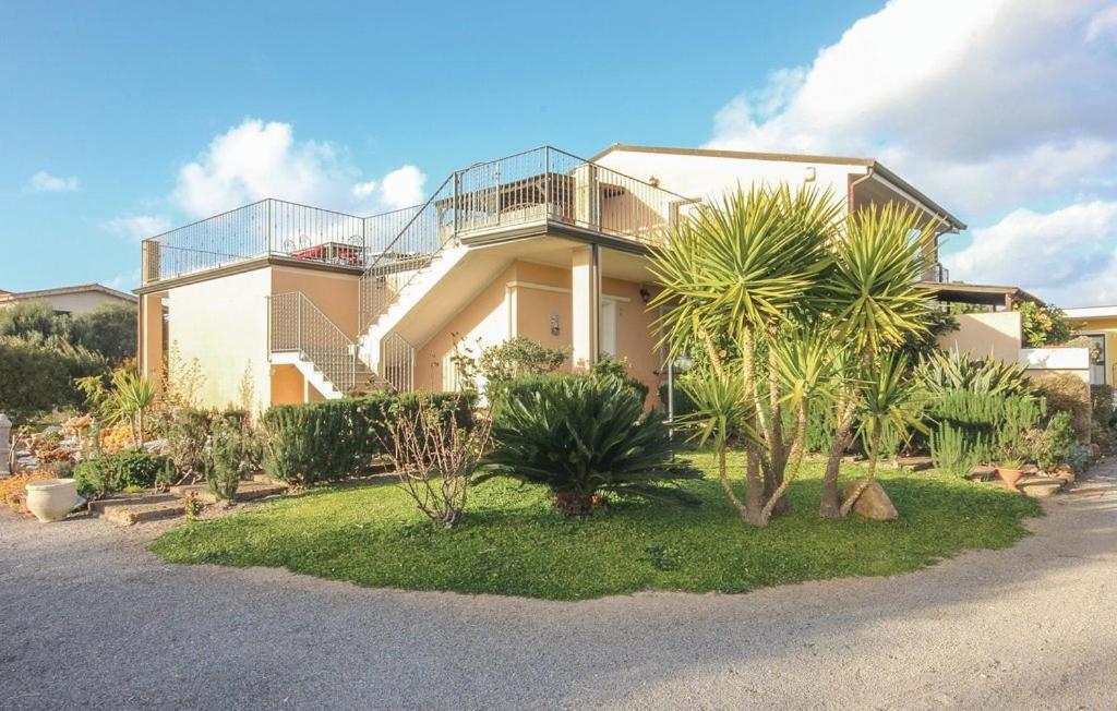 a house with a balcony and palm trees in front of it at Casa Vacanze Giovanna in SantʼAnna Arresi