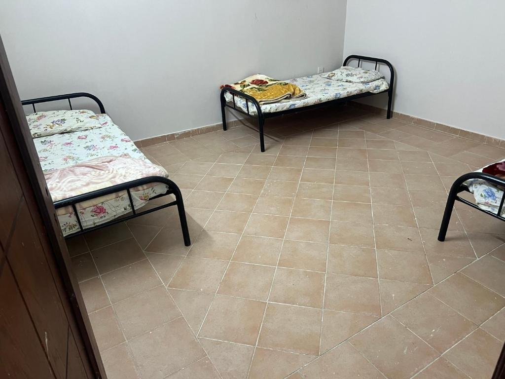 two beds in a room with a tile floor at شقة تبعد عن الحرم ١٠ د in Al Hindāwīyah