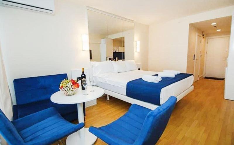 Schlafzimmer mit einem Bett, einem Tisch und blauen Stühlen in der Unterkunft Batumi Orbi City Twin Towers C-block 2659 in Batumi